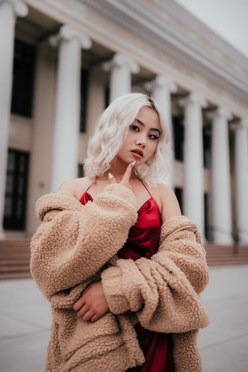 beautiful blonde woman on a red silk dress posing in city