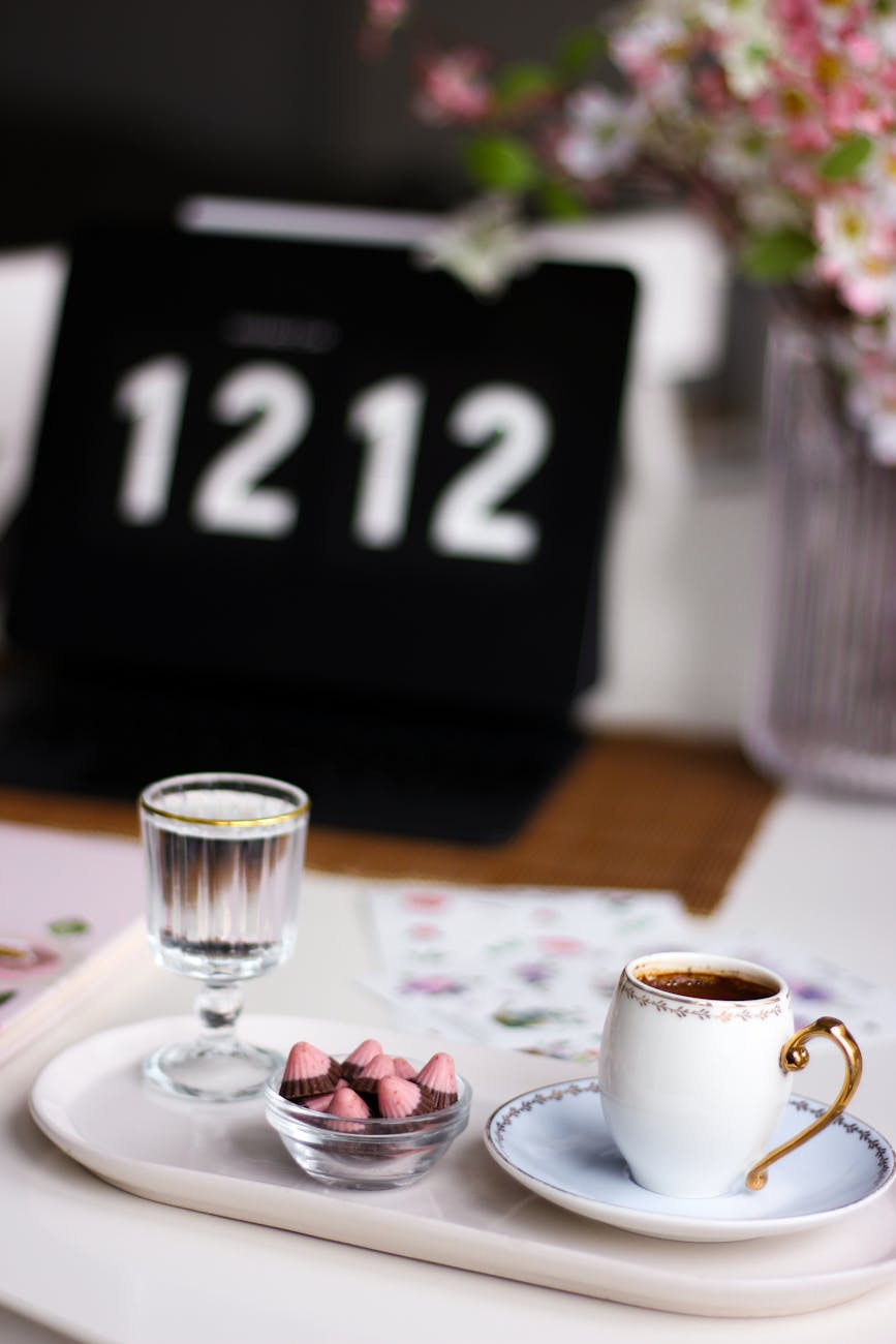 a cup of coffee a glass of water and sweets on a tray
