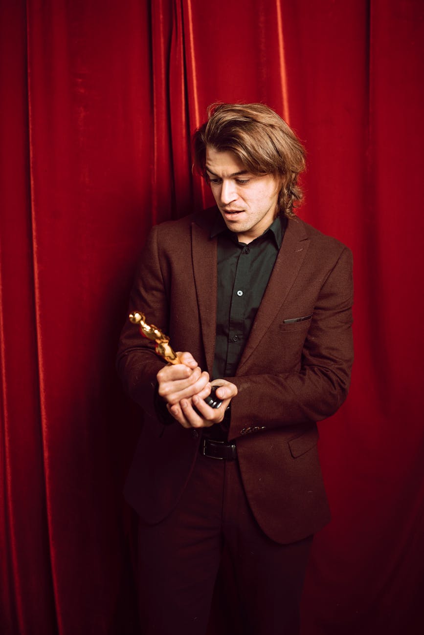 Gala Ready: High-Volume Glamour at Just For Hair 1 aa man wearing a suit holding a golden trophy near the red curtain