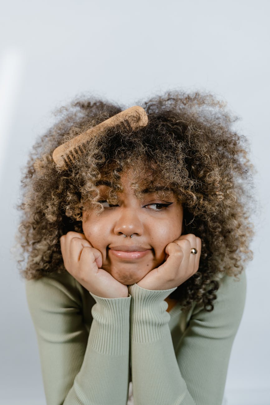 Natural – Natural Hair Care: The High-Performance Revolution at Just For Hair 1 a woman posing with a wooden comb on her hair