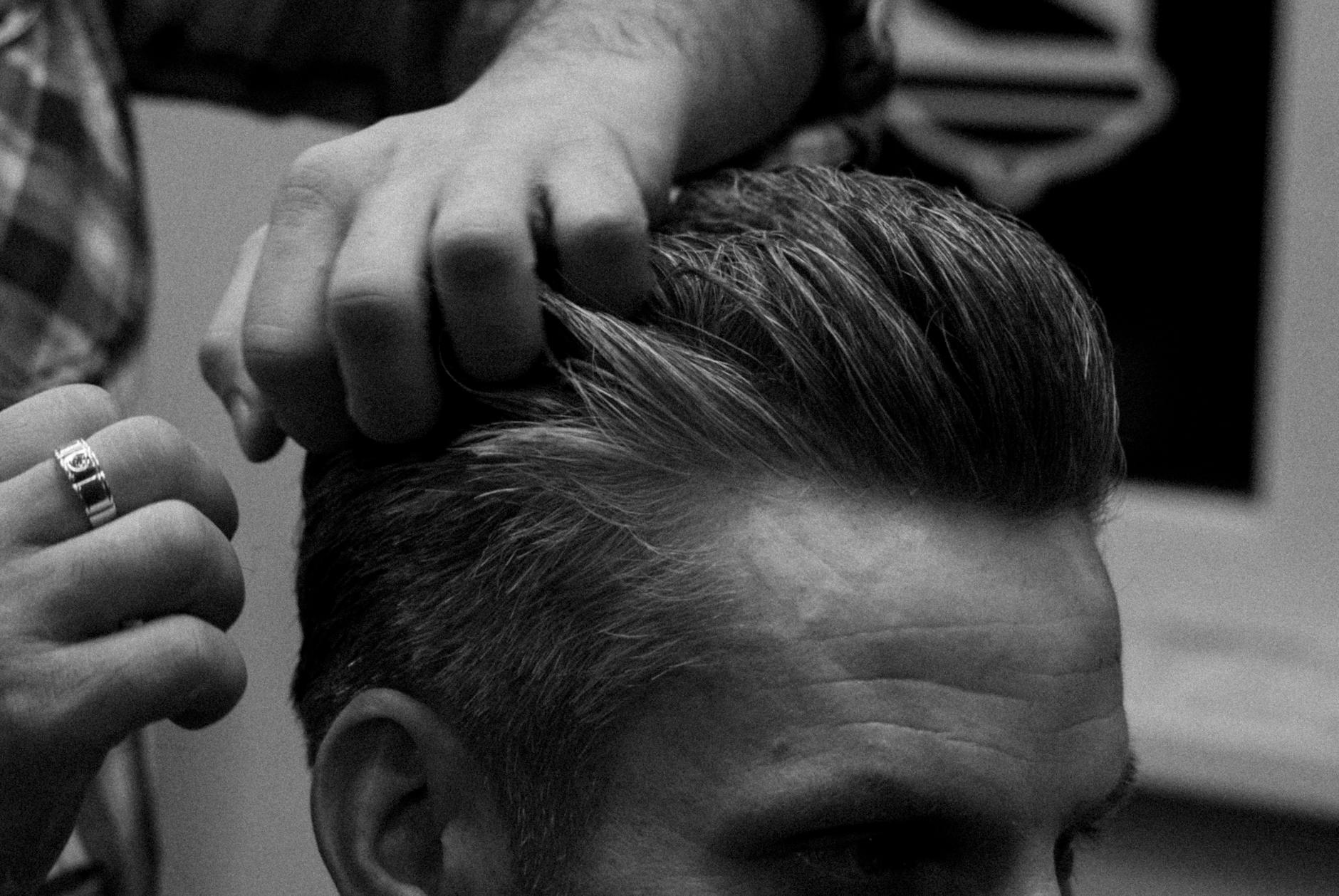 Sharp & Defined: Men’s Hair Styling Tailored to Your Personal Style 1 grayscale photo a hairstylist fixing client s hair