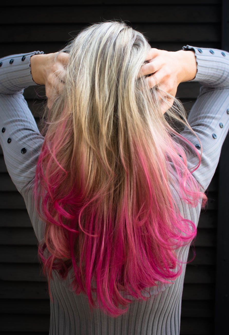 From Platinum to Pink: A Neon Hair Transformation Journey 1 woman in gray long sleeved top holding hair