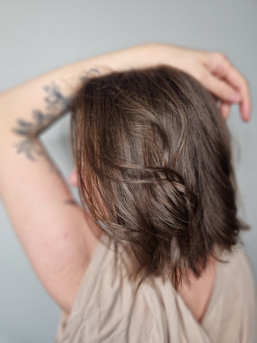 back view of a woman with tattoos holding hand in hair