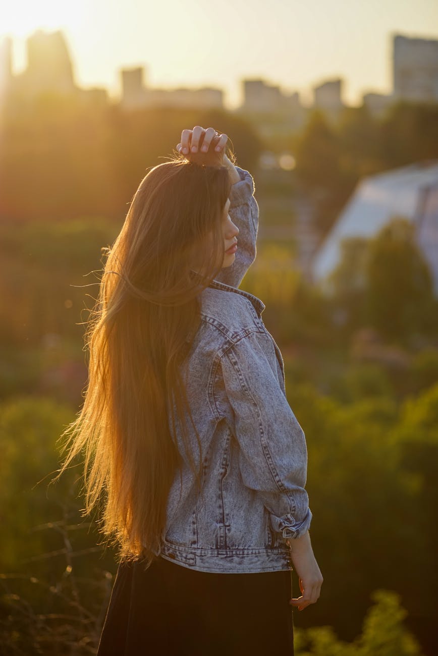 a woman with long hair standing outside at sunset