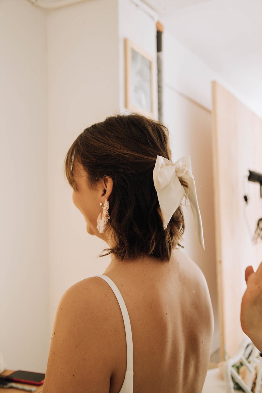a bride with a white bow in hair preparing for a wedding ceremony