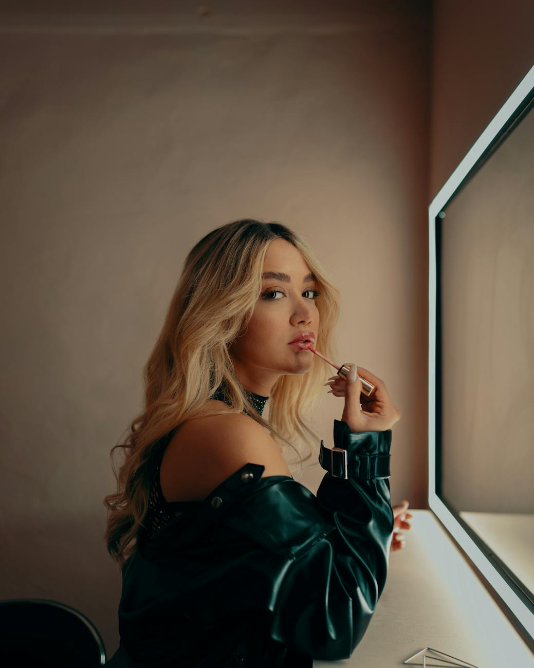 stylish young woman applying makeup at vanity