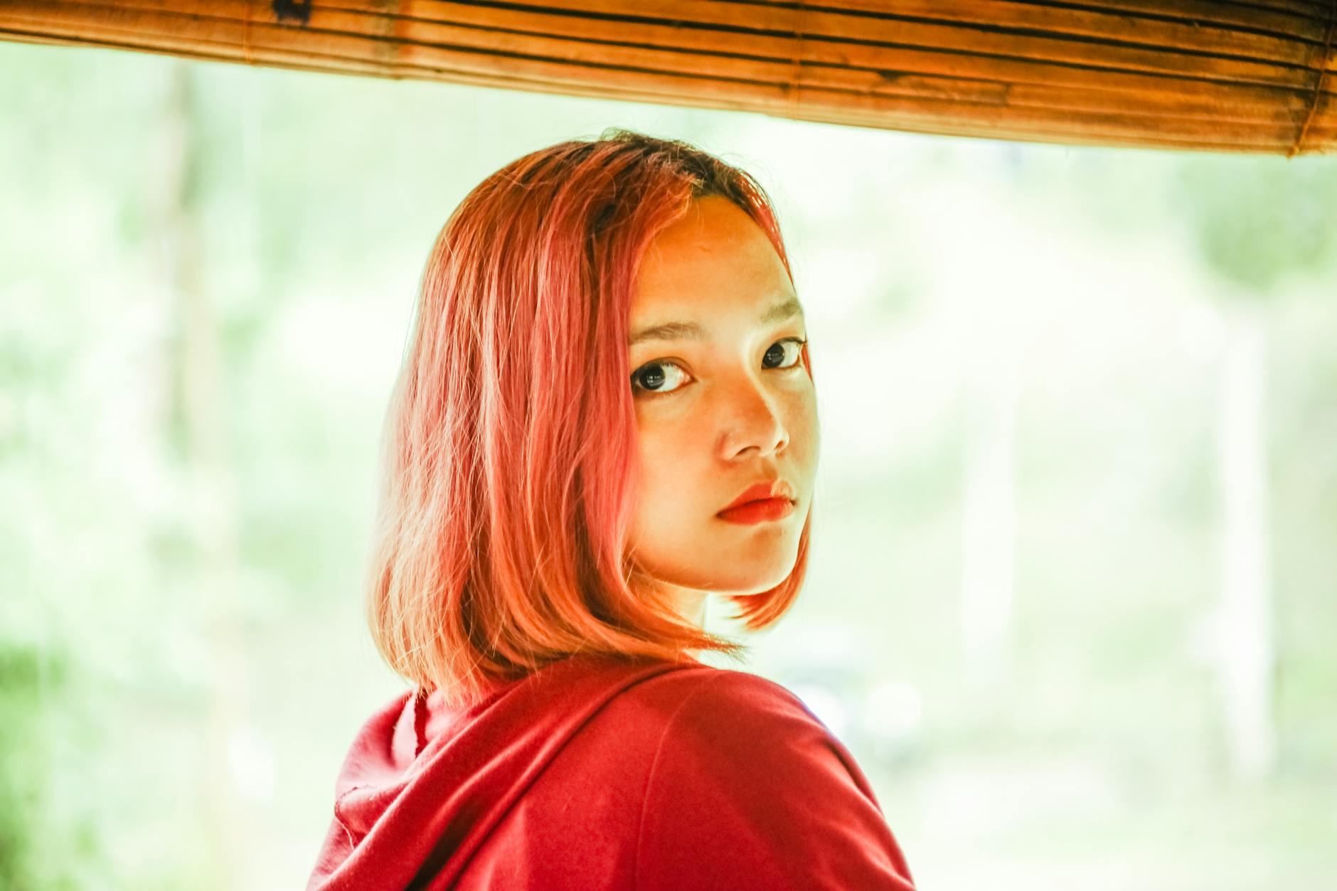 Chromatic Fire: Vibrant Red Hair Coloring for Eye-Catching Beauty 1 a woman wearing a red hoodie jacket