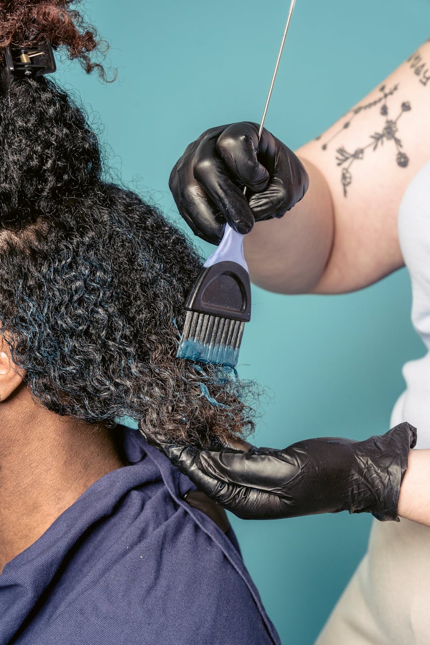 The Chemistry of Fashion Colors: Why Formulation Matters 1 woman applying dye on hair of black man