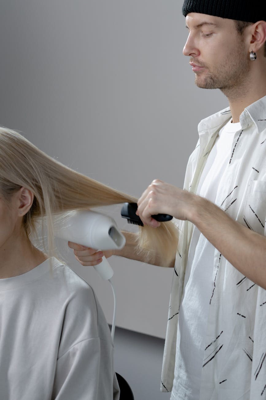 photo of a man blow drying a woman s hair