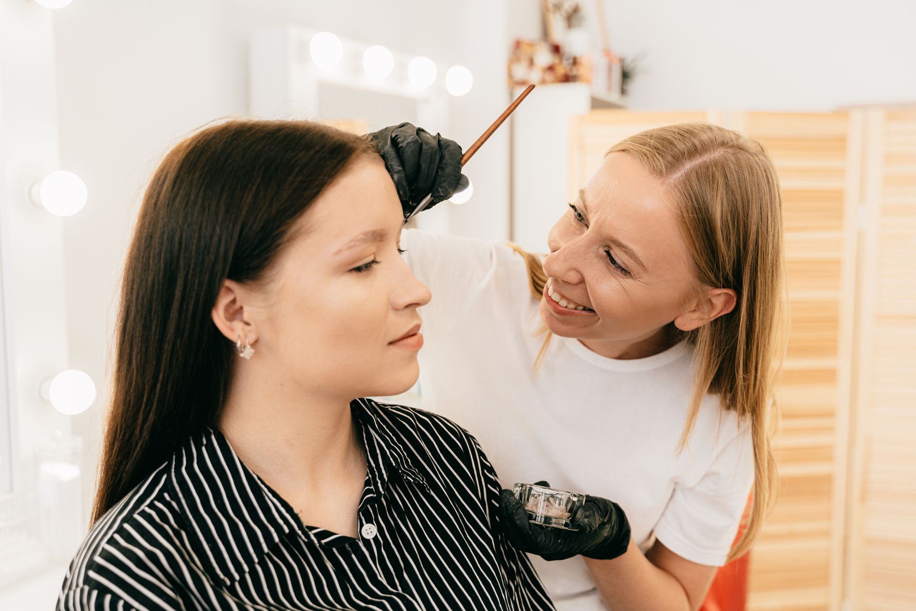 woman in black and white stripe shirt getting her brows done