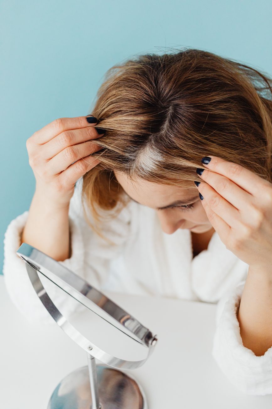 Seamless Melt: Avoiding Harsh Lines with a Custom Root Smudge 1 woman looking at her grey hairs in mirror
