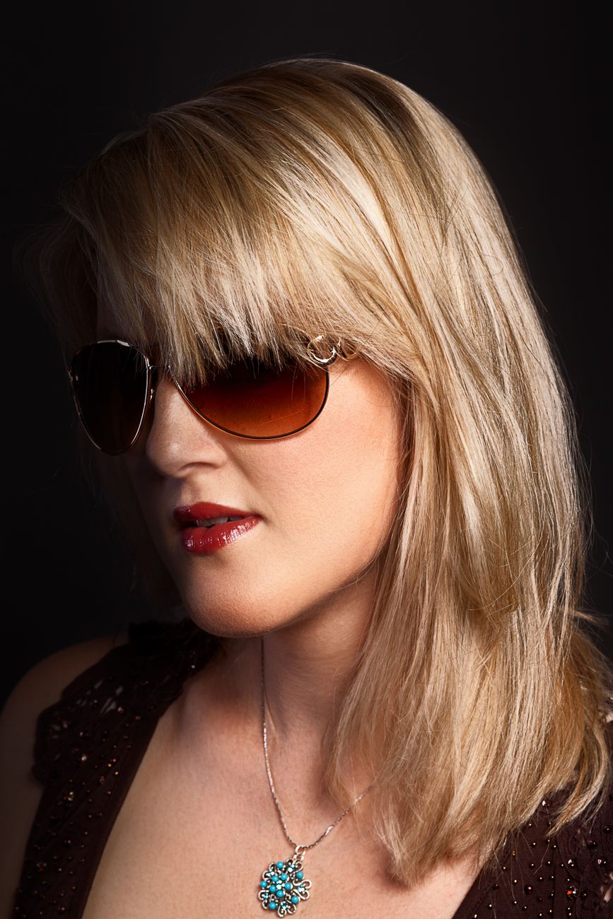 close up photo of a woman with blond hair wearing brown sunglasses