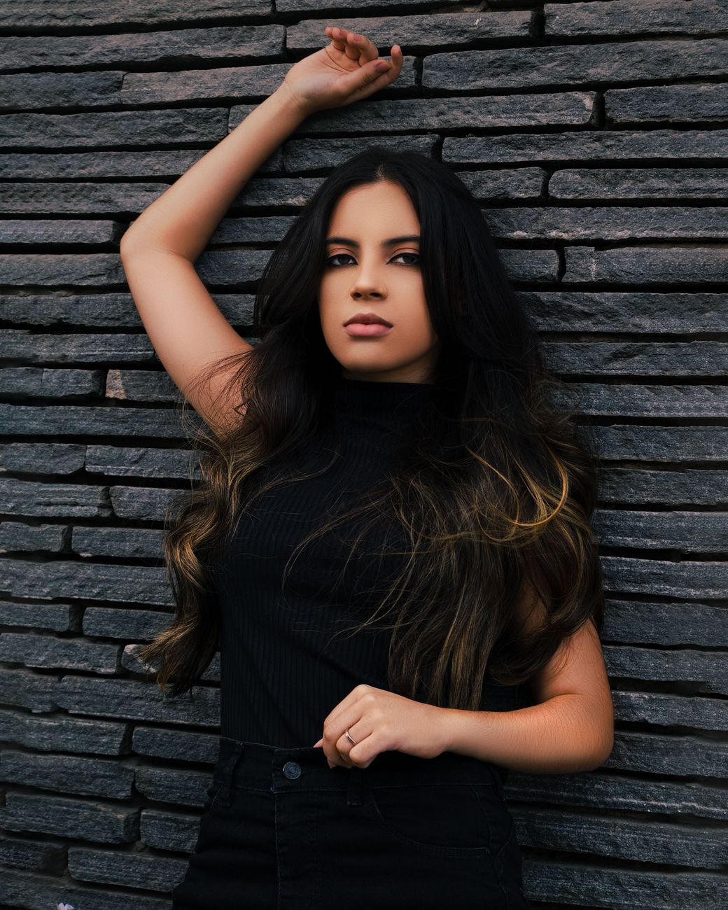 a woman in black tank top leaning on the wall