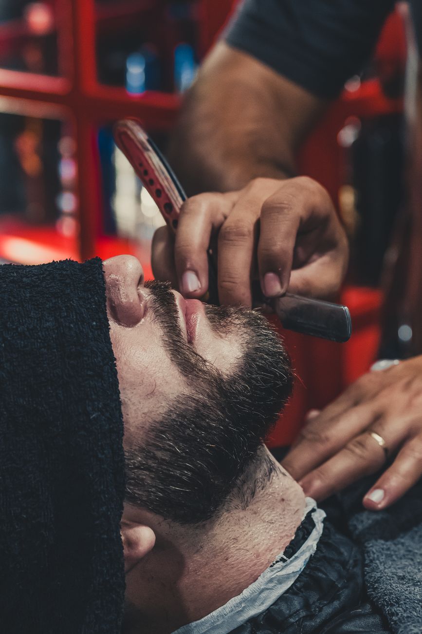 Beard Trimming and Haircut Coordination: Creating a Unified Look 1 barber shaving a mans beard