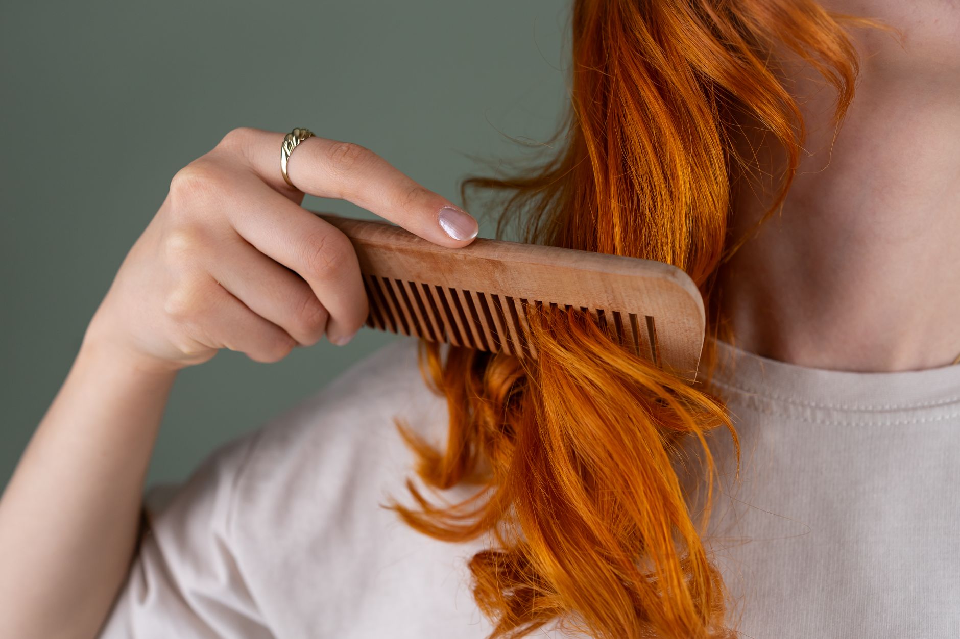 woman combing vibrant red hair with wooden comb