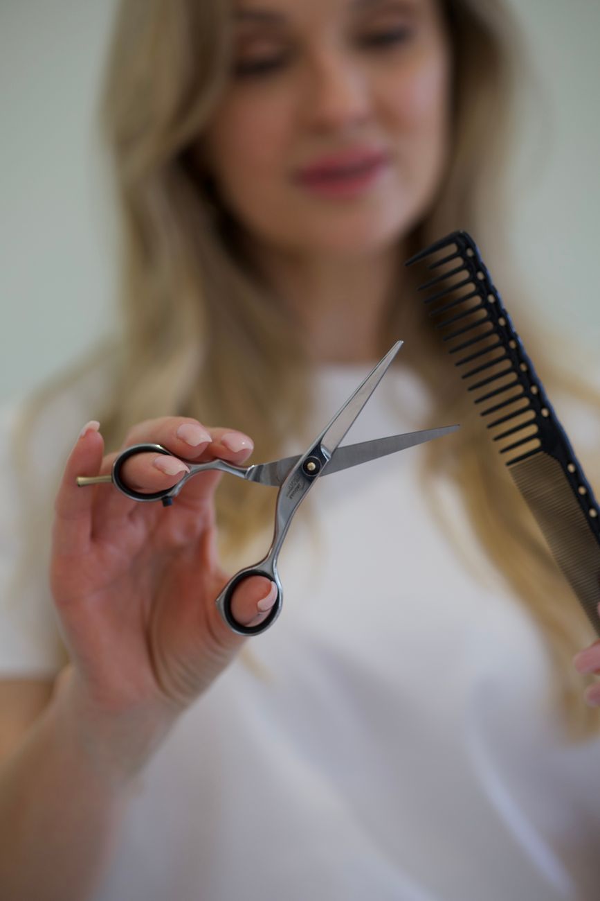 Reversing the Clock: Volumizing Cuts and Colors That Illuminate Your Face 1 hairdresser holding scissors and comb in a salon