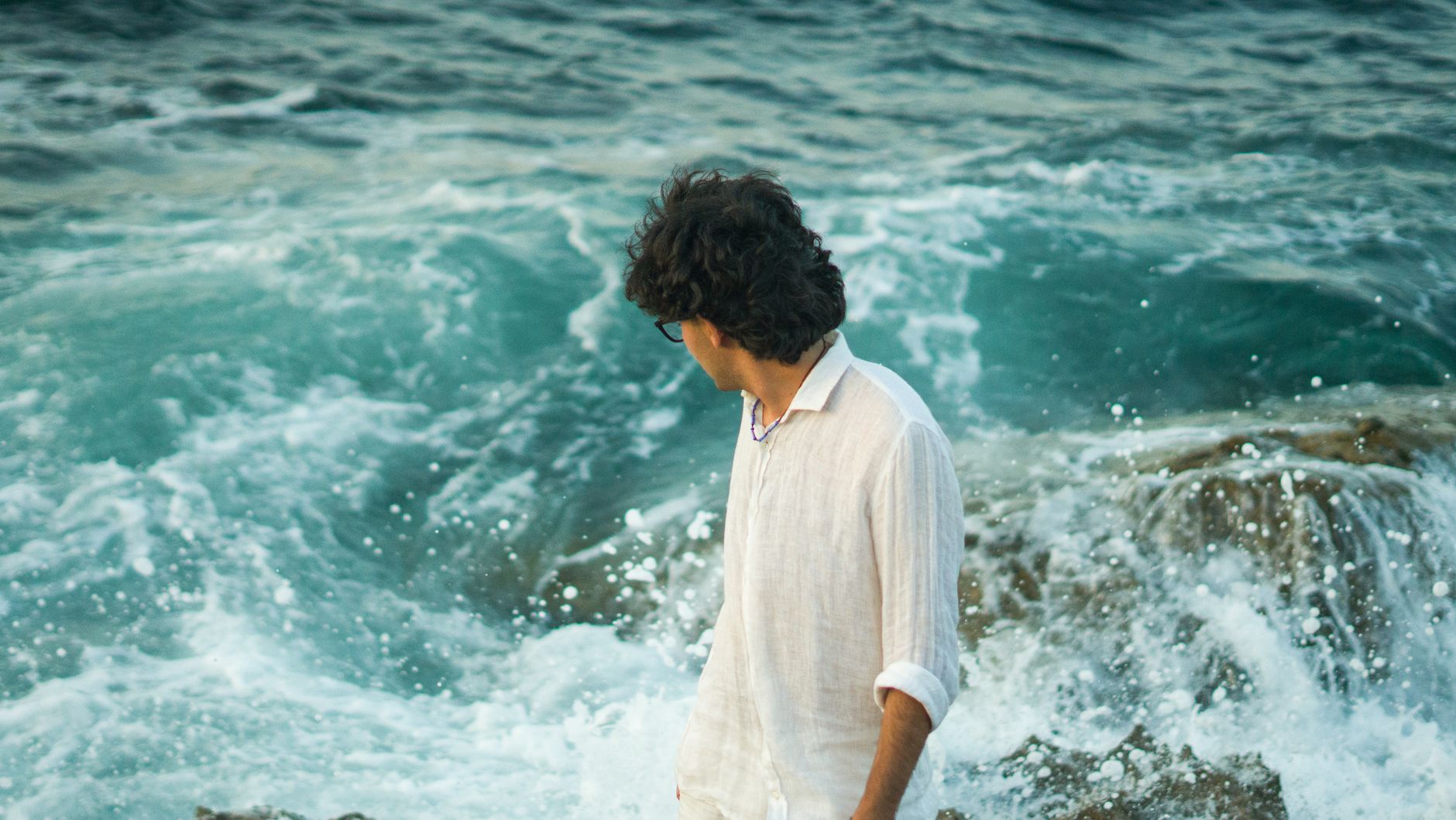 man in white shirt by the ocean waves