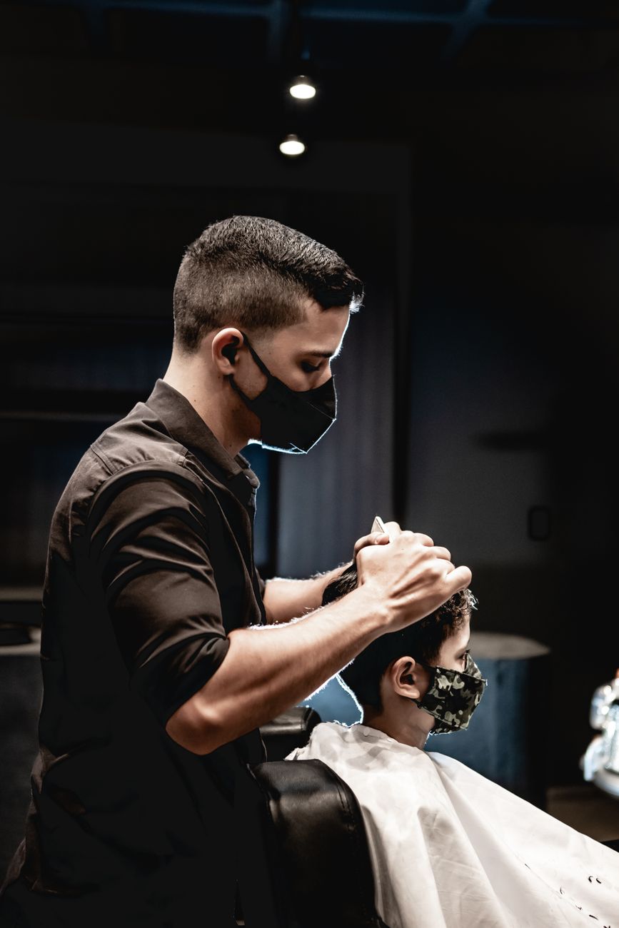 The Science of Lightener: How Balayage Helps Preserve Hair Health 1 a barber giving a haircut to a boy