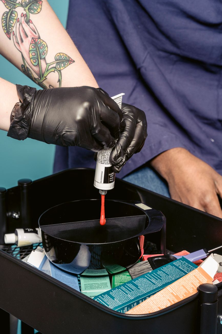 unrecognizable hairstylist preparing paint near client