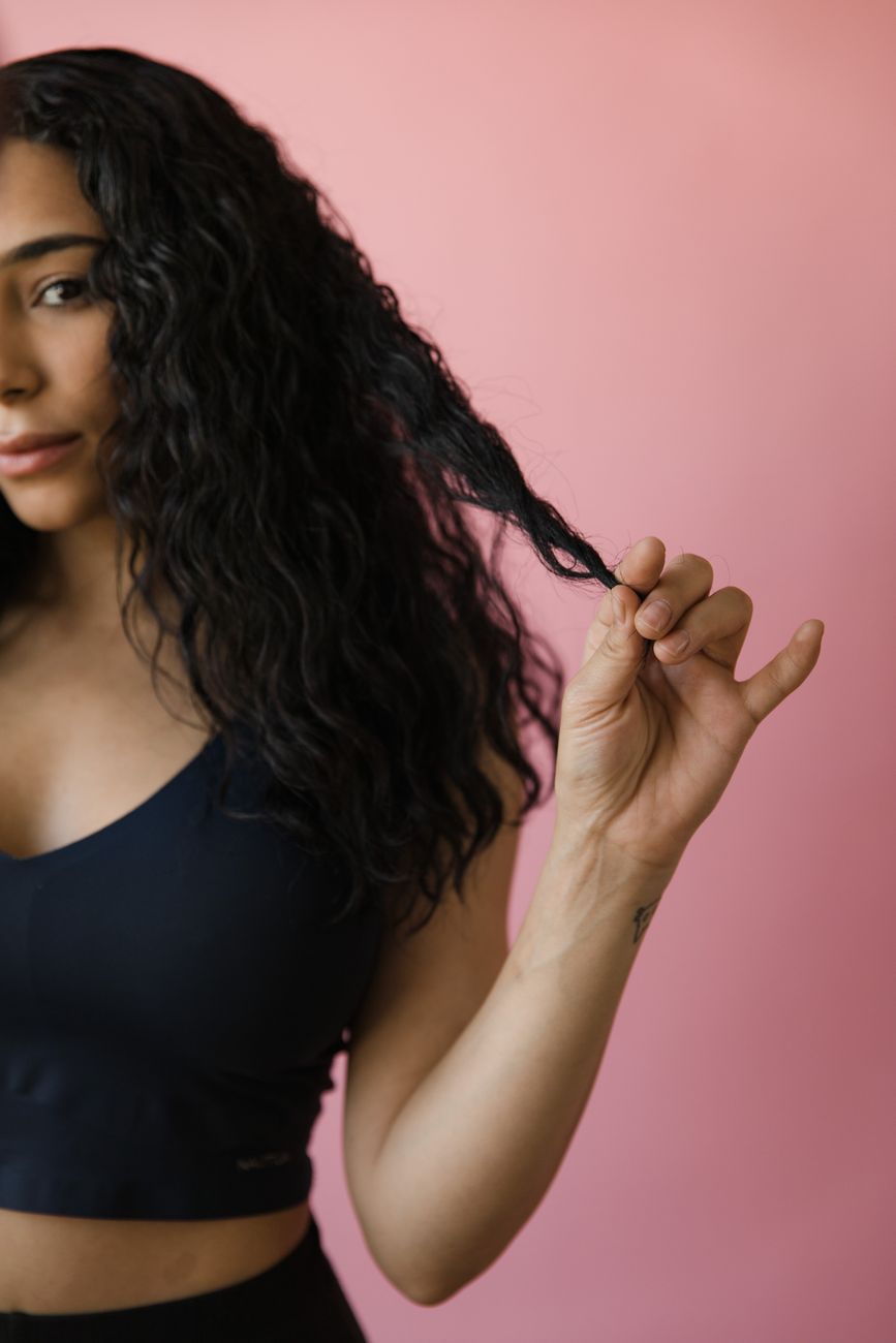 a woman in black tank top holding her hair
