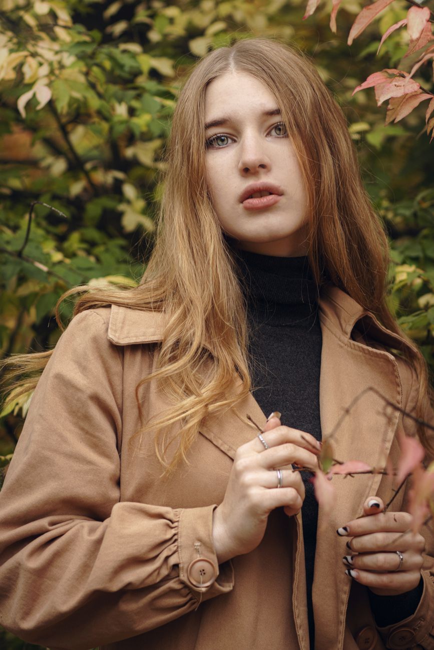 a woman wearing a brown jacket over a black turtle neck shirt