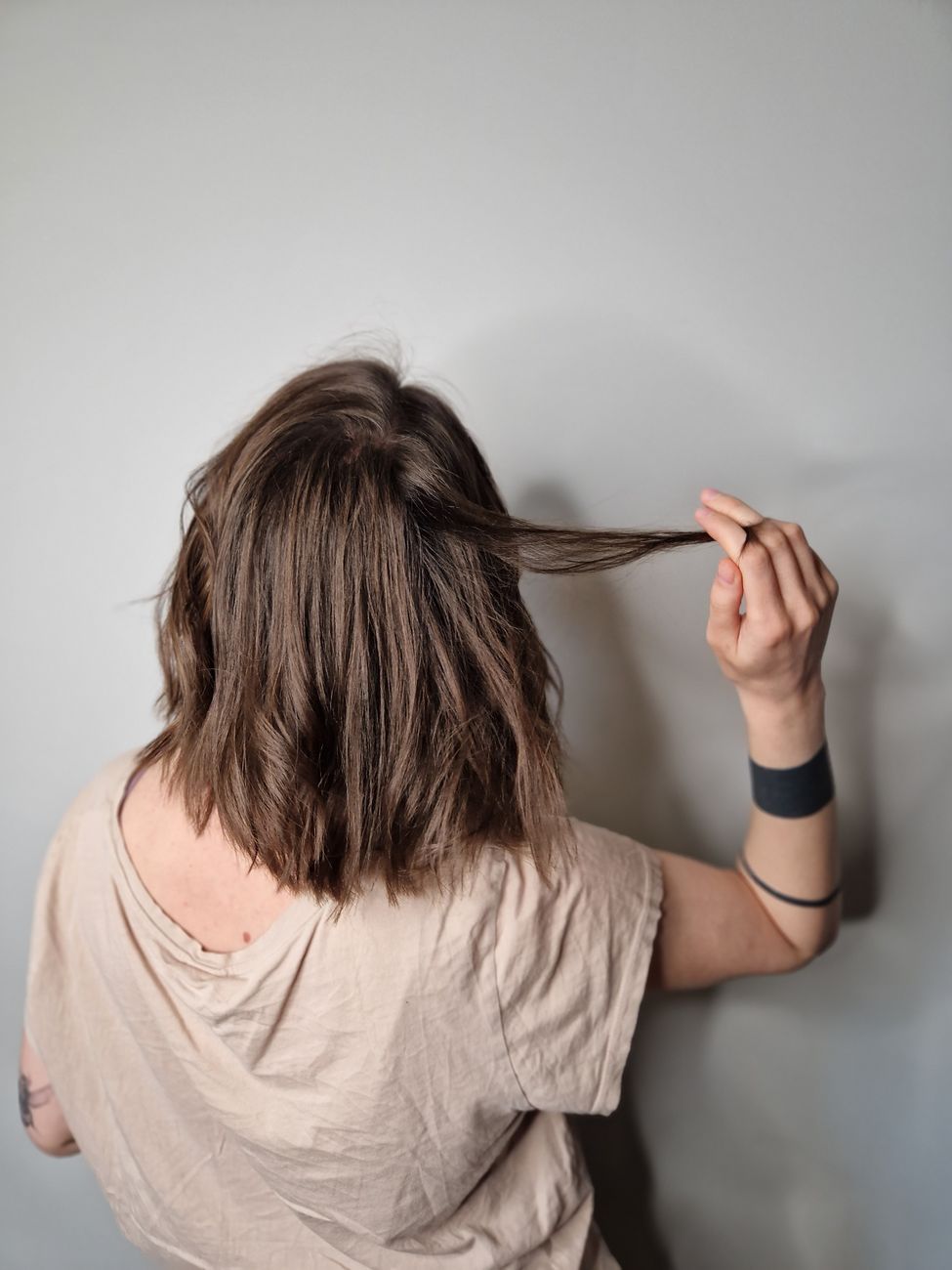 Micro Balayage Accents for Short Cuts 1 back view of a woman with tattoos holding hand in hair