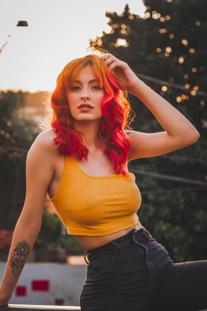 stylish tattooed ethnic woman with red hair in evening
