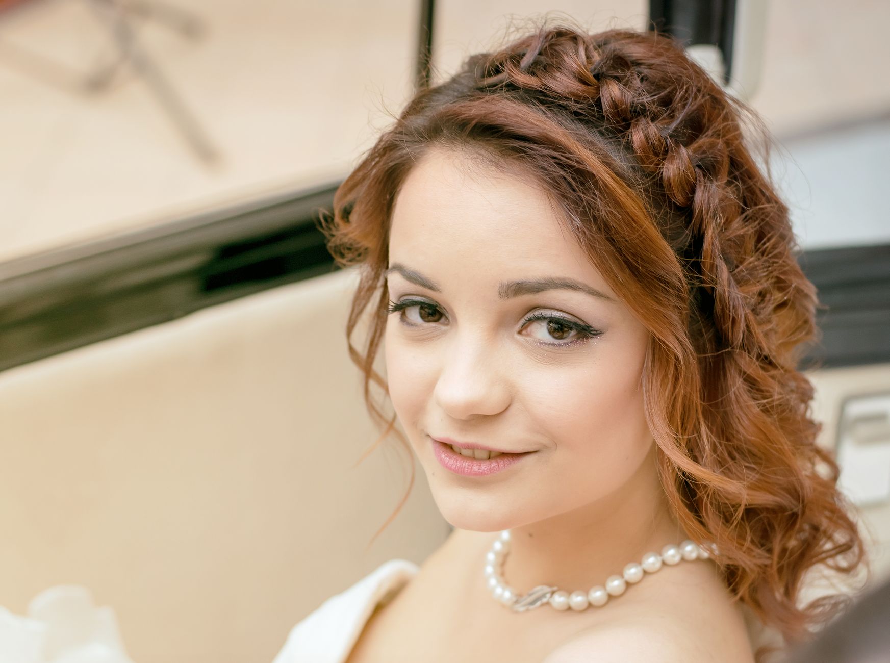 a woman with braided hair wearing a pearl necklace
