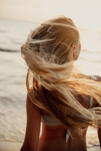 Summer Hair Care Survival Guide: UV Rays, Chlorine, and Humidity 1 back view of a woman in a bikini flipping her hair